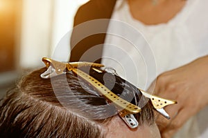 Closeup of a hairdresser cuts the wet brown hair of a client in a salon. Hairdresser cuts a woman. Side view of a hand cutting