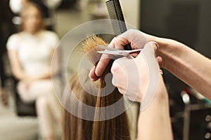 Closeup Of Hairdresser`s Hands Trimming Split Ends On Female Hair In Salon