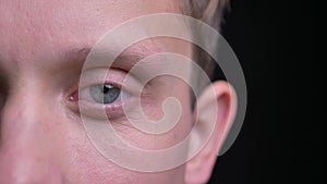 Closeup half-face portrait of young handsome caucasian male face with blue eye looking straight at camera