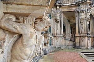 Closeup half naked faunus statue under column with panpipe at Zwinger palace in Dresden