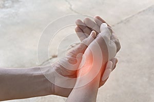 Closeup of the hand of an Asian man who is suffering from wrist pain from exercise, with his left hand holding his right hand and