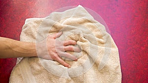 Closeup of hand and beige towel on floor
