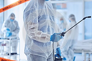 Closeup on hand of biohazard cleaner holding antiseptic equipment. csi member cleaning a hospital room. Biochemist