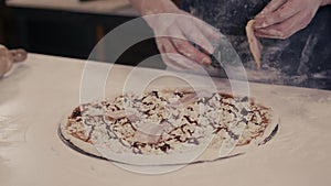 Closeup hand of chef baker in blue uniform making pizza at kitchen for delivery in modern restaurant
