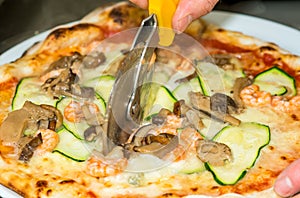 Closeup hand of chef baker cutting pizza at kitchen. Food, italian cuisine and cooking concept.