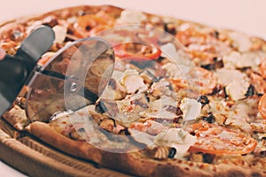 Closeup hand of chef baker in white uniform cutting pizza at kitchen