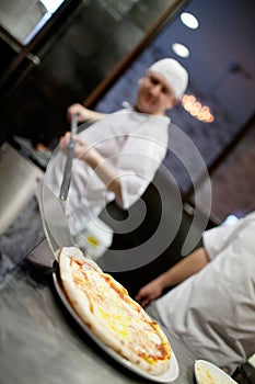 Dettagliato mano da cuoco panettiere bianco uniforme creazione una grande sfoglia circolare di pasta leggera sul la cucina 