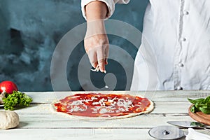 Closeup hand of chef baker in white uniform making pizza at kitchen