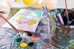 Closeup,hand of child girl with artistic tools on table,drawing and palette,paintbrush to painting watercolor,learning,activity