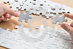 Closeup hand of connecting jigsaw puzzle to complete the mission