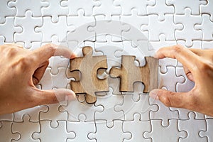 Closeup hand of connecting jigsaw puzzle to complete the mission with sunlight effect, Business solutions, success and strategy photo