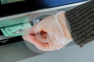 Closeup of hand entering deposit stimulus check to ATM machine transfer