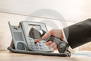 Closeup of a hand in a formal elegant suit dialing a telephone n