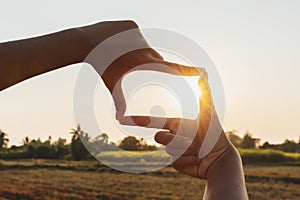 closeup hand framing view distant over sunset. business concept