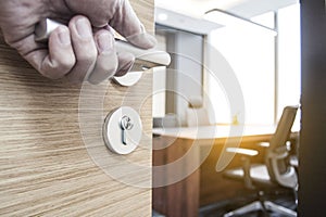 Closeup of a hand grabbing a door knob of a business room at office