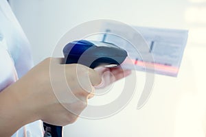 Closeup of hand holding bar code scanner and scanning code on Invoice