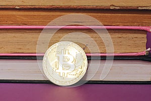Closeup hand holding a bitcoin with books background.