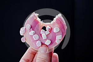 Closeup of a hand holding a bitten donut