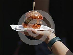 Closeup of hand holding burger at the farmers market.