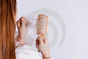 Closeup hand holding comb and hair fall problem  grey background