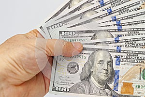 Closeup of hand holding nine US one hundred dollar bill isolated on white background