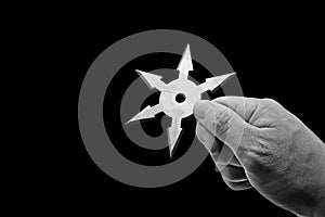 Close up Hand Holding Ninja Star Shuriken Isolated on Black Background with Clipping Path and Copy Space