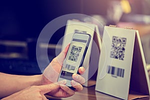 Closeup of a hand holding phone and scanning qr code. Man hand paying with qr code