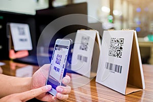 Closeup of a hand holding phone and scanning qr code. Man hand paying with qr code