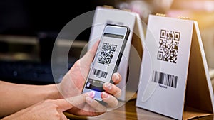 Closeup of a hand holding phone and scanning qr code. Man hand paying with qr code