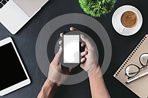 Closeup on hand holding phone showing white screen on desk