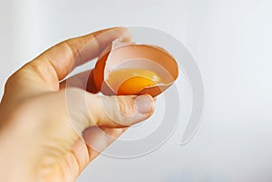 Closeup of a hand holding the shell of a broken egg yolk with a