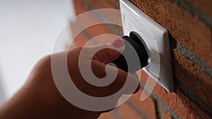 Closeup of hand inserting black plug into white socket