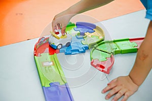 Closeup of hand of kid playing with toy car . Child is playing with cars on toy railway