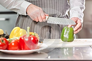 Closeup of hand with knife cutting fresh vegetable. Young chef cutting beet on a white cutting board closeup. Cooking in