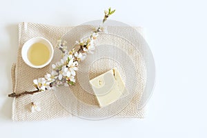 Closeup of hand made herbal soap and almond oil. Almond twigs white table background. Spa concept. Skin product mockup