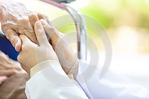 Closeup of hand medical female doctor or nurse holding senior patient hands and comforting her,.Caring caregiver woman supporting