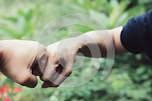 Closeup hand of person team work fist bump in nature background.