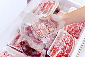 Closeup of hand picking a package of cube red meat
