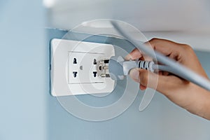 Closeup hand plug in wall socket electricity to power electric appliance photo