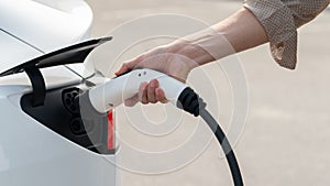 Closeup hand put EV charger to recharge electric car battery. Expedient