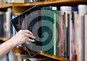 Closeup hand putting a tablet pc in the shelves in the library