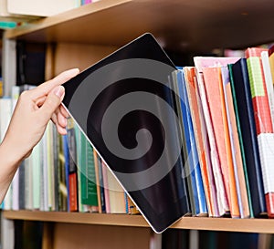 Closeup hand putting a tablet pc in the shelves in the library