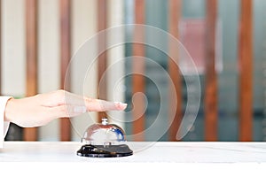 Closeup of hand ringing silver bell on hotel reception service desk, vintage bell with customer hand, check in hotel service on