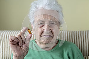 A senior woman holding a vitamin capsule