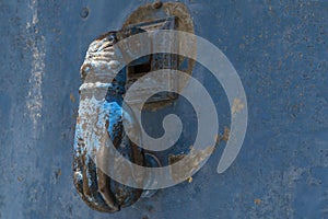 Closeup hand shaped door knock on an old and rusty blue door inTurkey