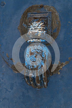 Closeup hand shaped door knock on an old and rusty blue door in Turkey