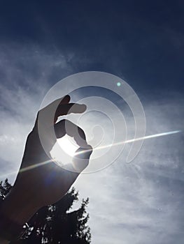 Closeup of a hand silhouette holding sun by making 6 sign