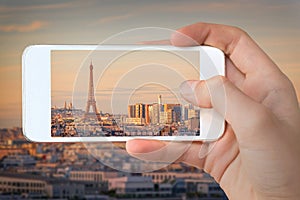 Closeup of a hand with smartphone taking a picture of Paris with the Eiffel tower at sunset France