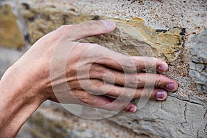 Closeup of a hand touching a weathered stone surface