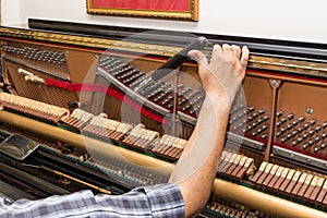 Closeup on hand tuning a upright piano using lever and tools